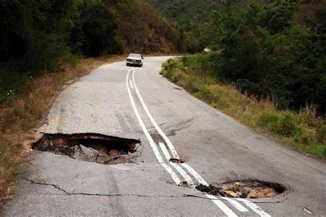 A car navigating a rough, unpaved road with visible bumps and uneven terrain, illustrating challenges drivers face on difficult road conditions.